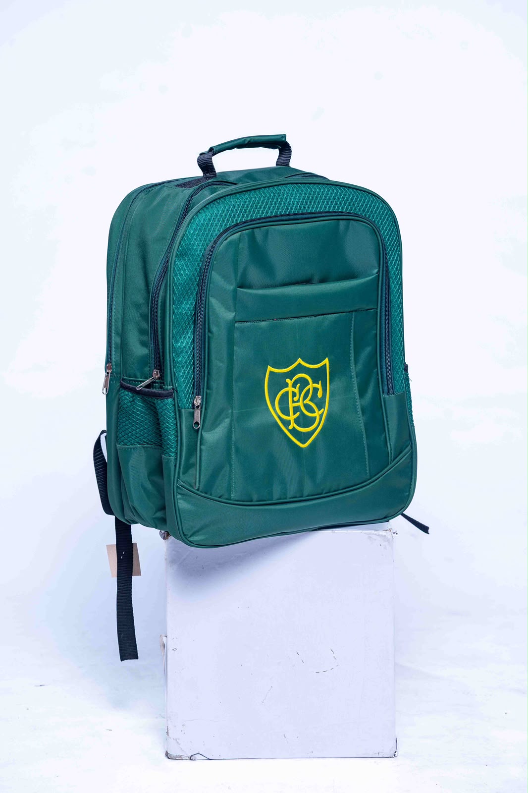 Green school backpack with yellow embroidered crest